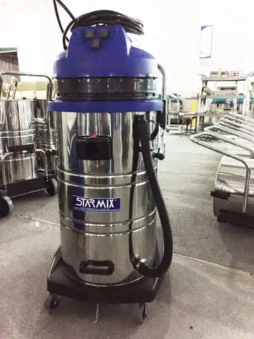 Aspirador industrial de pó e líquido com tanque em aço inox, três motores e rodízios reforçados para limpeza pesada em fábricas.